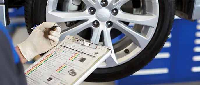 A Subaru service technician reviewing a multipoint inspection form.