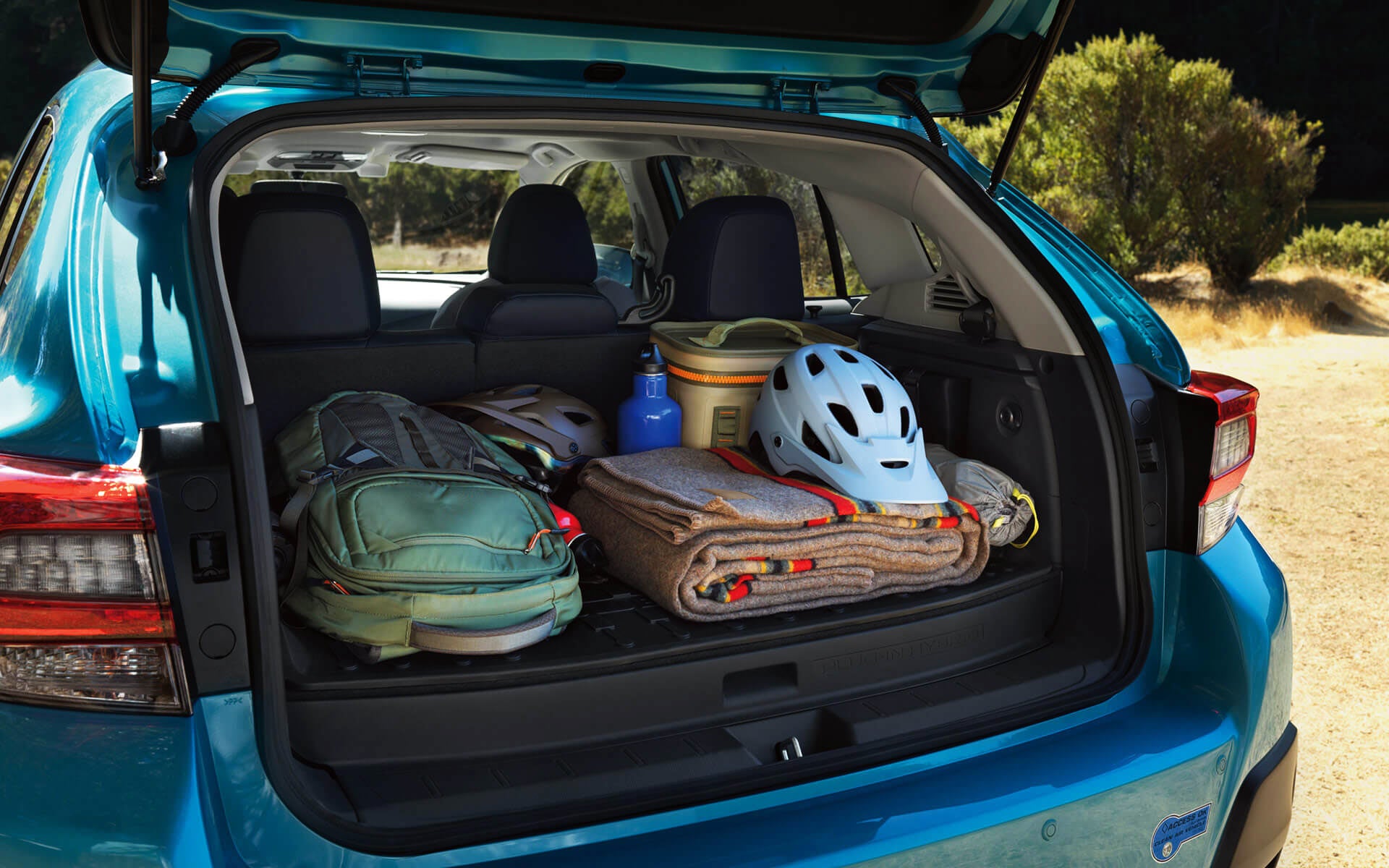 A backpack, blanket, and bike helmet in the rear cargo area of a Crosstrek Hybrid | Subaru Superstore of Surprise in Surprise AZ